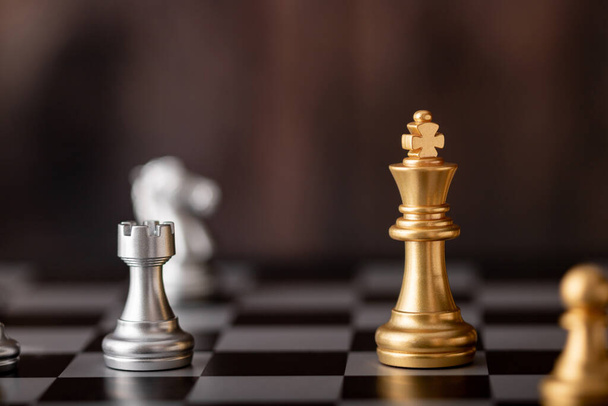 Rey de oro en el juego en el tablero de ajedrez con fondo de madera - Foto, imagen