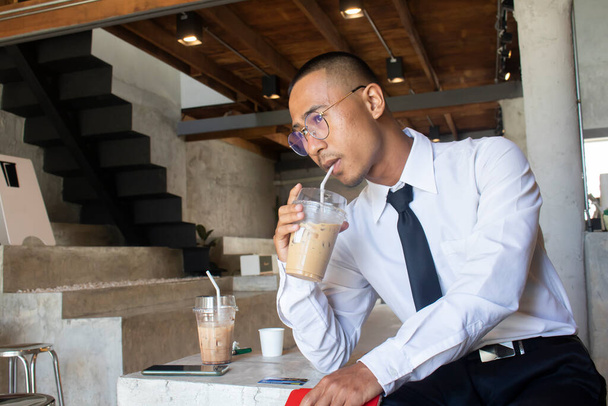 アジアのビジネスマンがカフェでアイスコーヒーを飲む - 写真・画像