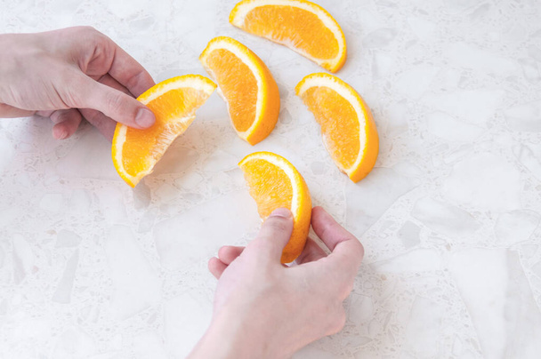 Women's hands hold juicy orange slices on the table - Photo, image