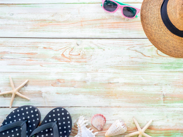 Beach accessories, seashells, dried finger starfish, straw hat, sunglasses and black polka dot flip flops on vintage wooden plank with space. Travel and vacation summer holiday background, top view. - Photo, Image