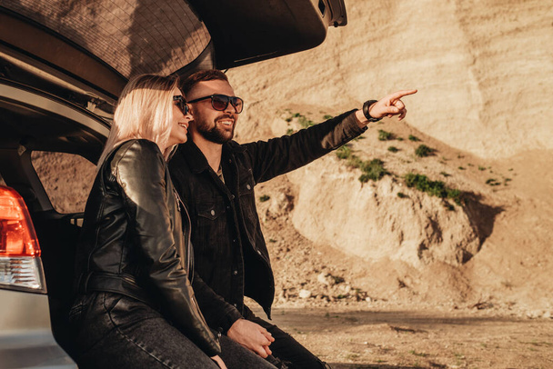 Happy Young Traveler Couple Dressed Alike in Black Leather and Jeans Jacket Having Fun Time on Road Trip Outside City - Photo, Image