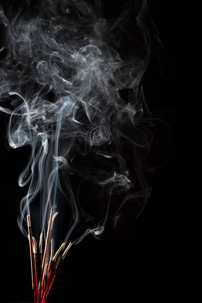 Creative illustration of incense stick aroma with smoke isolated on black background - Foto, Imagem
