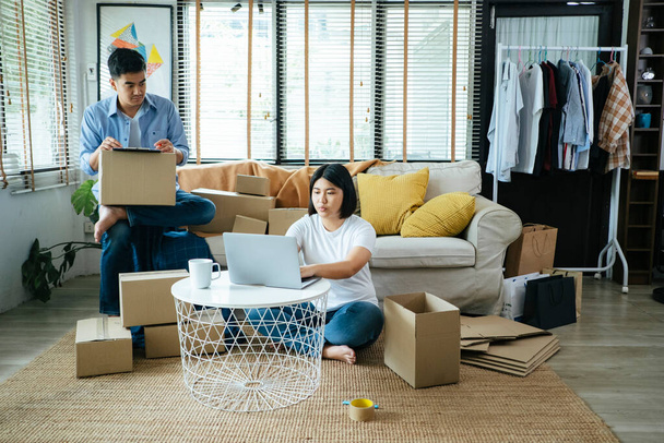 Man and woman sitting in living room and pack the goods as online order. - Photo, image