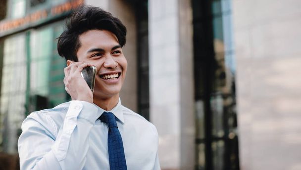 Retrato de un feliz empresario sonriente hablando por teléfono móvil en la ciudad urbana. Lifestyle of Modern People. Edificio moderno como fondo - Foto, imagen