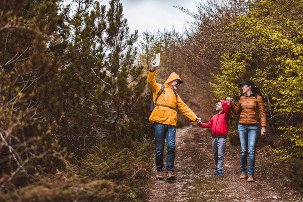 Happy family walking with backpacks in woods and having fun. - 写真・画像