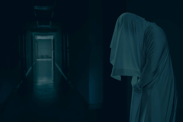 L'homme est en vêtements blancs et montre un visage effrayant regardant un couloir d'hôtel effrayant, ressembler à un fantôme dans la nuit pour le concept de festival d'Halloween, Copier l'espace - Photo, image