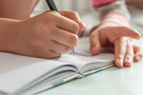 детские руки держат ручку. Малыш что-то пишет в блокноте - Фото, изображение