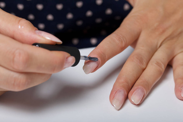 A woman gives herself a manicure. Apply new nail Polish with a brush. Taken in close-up. - Foto, Imagem