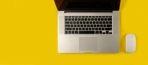 Top view of laptop and mouse on yellow background.Flat lay composition with notebook and mouse on yellow background - Fotó, kép
