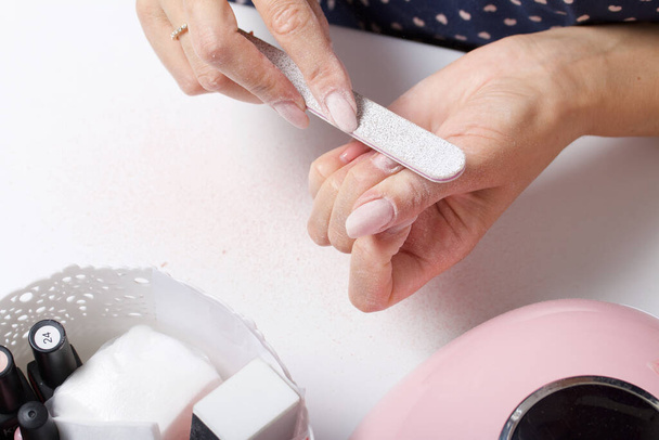 A woman makes her own manicure. Removes old nail Polish with a nail buff. Taken in close-up. - Foto, Bild
