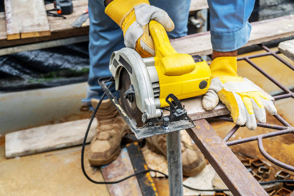 Carpenter using circular saw for cutting wooden boards with power tools, construction and home renovation, repair and construction tool - Foto, Imagen