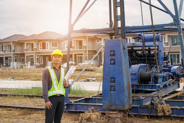 Aasian liikemies rakennusinsinööri työntekijä suojakypärä ja piirustukset paperi käsillä talon rakennustyömaalla - Valokuva, kuva