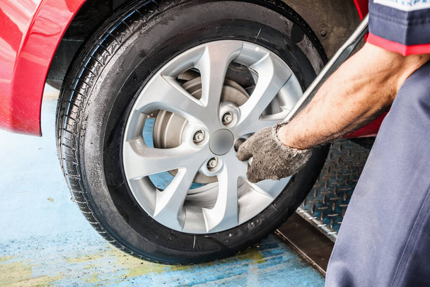 Tire replacement service, Mechanic with wrench working at auto repair shop changing car wheel - Φωτογραφία, εικόνα