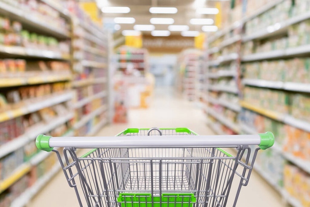 Empty shopping cart with abstract blur supermarket discount store aisle and product shelves interior defocused background - Photo, Image