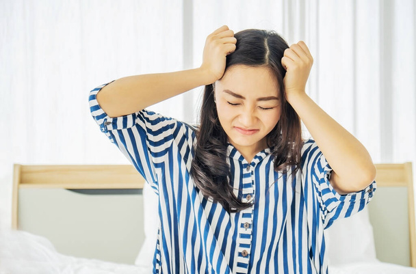 Mooie Aziatische vrouwen raken hoofd lijden aan migraine of hoofdpijn en voelen spanning en serieus op bed, slecht nieuws - Foto, afbeelding