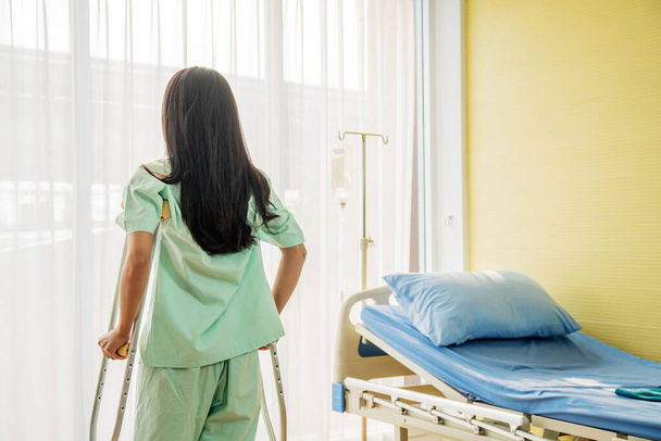 A nő beteg áll, és használja mankó várja az orvosi rendelőben - Fotó, kép