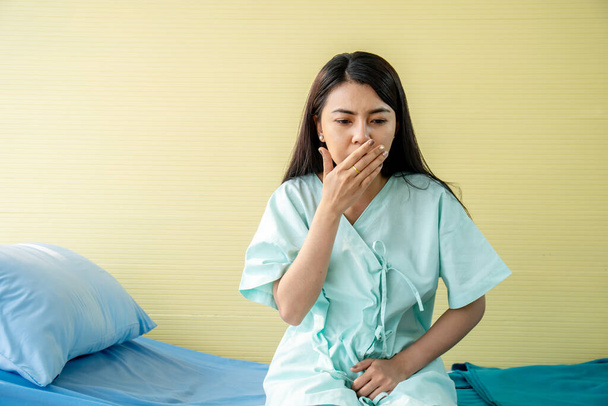 Γυναίκα ασθενής που πάσχουν από πόνο στο στομάχι και ναυτία, ενώ κάθεται στο κρεβάτι στο νοσοκομείο, κοιλιακό άλγος, τροφική δηλητηρίαση - Φωτογραφία, εικόνα
