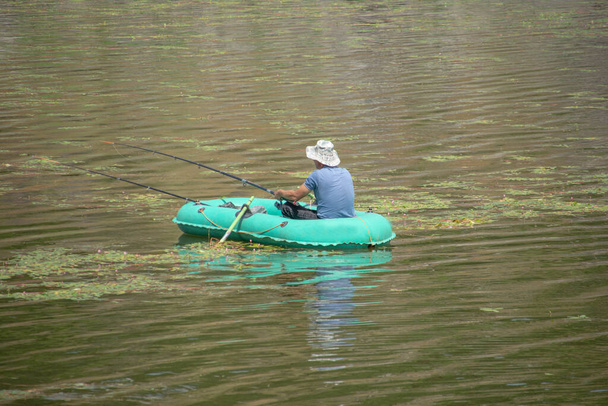 Un pêcheur sur un bateau. Pêcheur capture des poissons dans le lac - Photo, image