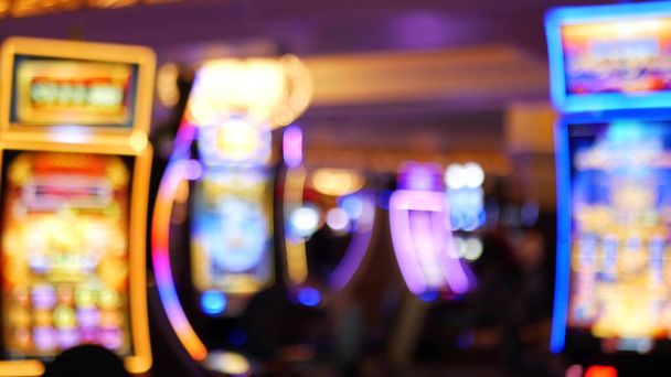 Las máquinas tragamonedas desenfocadas brillan en el casino en la fabulosa Las Vegas Strip, Estados Unidos. Desenfocado juego jackpot ranuras en el hotel cerca de la calle Fremont. Máquina de fruta de neón iluminada para jugar y apostar dinero de riesgo. - Foto, Imagen