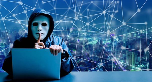 Anonymer Computerhacker in weißer Maske und Kapuzenpulli. Verdunkeltes dunkles Gesicht, Schweigegegeste vor modernem Hintergrund der Stadt, Datendieb, Internet-Angriff, Darknet und Cyber-Sicherheitskonzept. - Foto, Bild