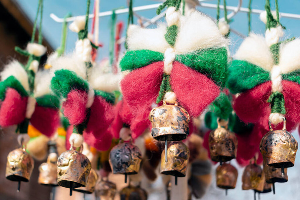 Měděné zvonky s ovčí vlnou luky v barvách bulharské vlajky. Tradiční bulharské etnické suvenýry. Ručně vyráběné dekorace na svátky - Vánoce a jara Evropy. Selektivní zaměření - Fotografie, Obrázek