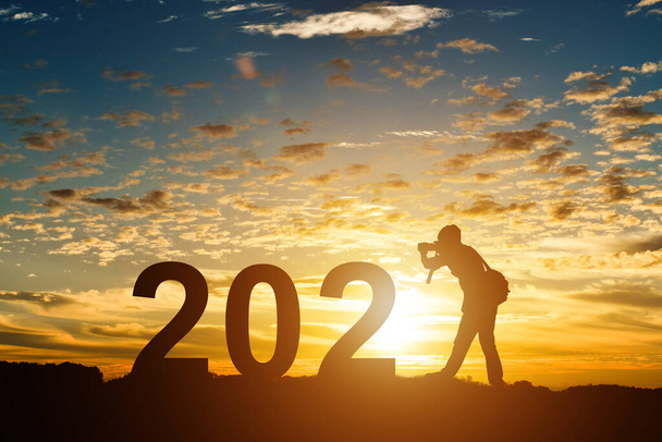 Silhouette de photographe prenant des photos en 2021 ans au lever ou au coucher du soleil, avec espace de copie. Idée pour bonne année 2021. - Photo, image