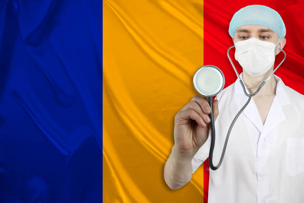 male doctor with a stethoscope on the background of the silk national flag of Romania, concept of national medical care, health, insurance, tourism - Foto, Bild