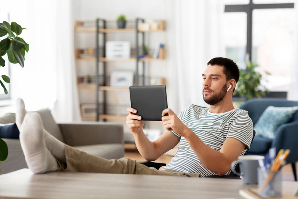 man with tablet pc and earphones at home - Foto, imagen