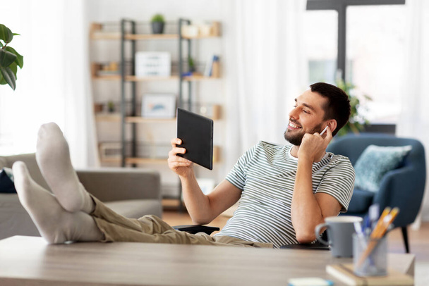 happy man with tablet pc and earphones at home - Photo, image