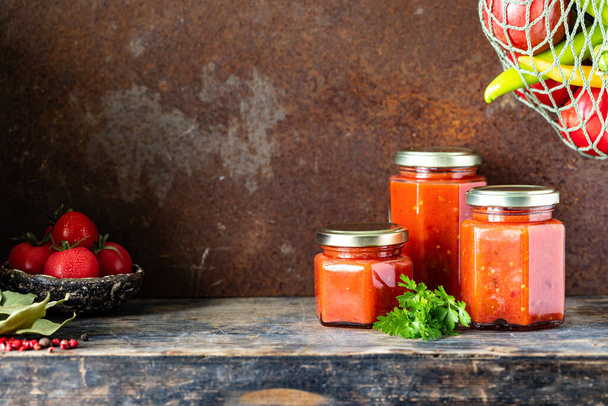 Several glass jars with homemade tomato sauce on a side wooden table. - Fotografie, Obrázek
