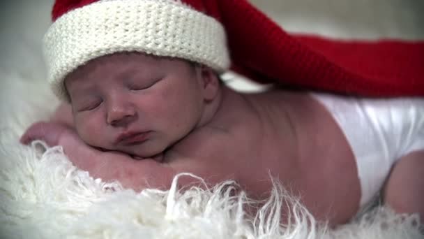 Baby in white diapers with a long red christmas hat on the head - Footage, Video