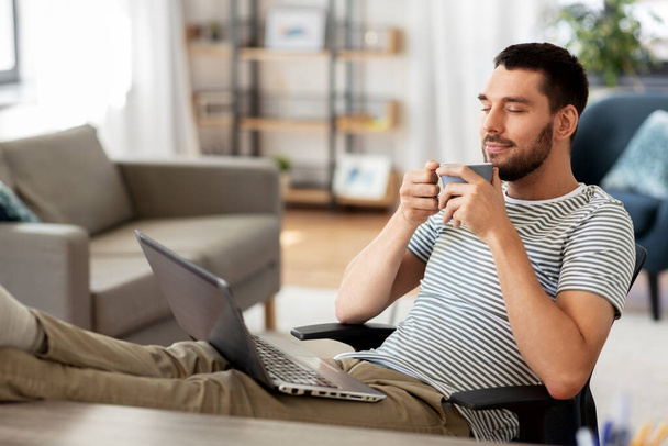 happy man with laptop drinking coffee at home - Zdjęcie, obraz