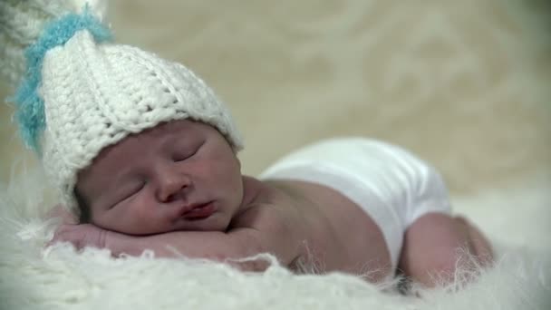 Pequeño bebé acostado sobre una manta salada con una gorra blanca
 - Metraje, vídeo