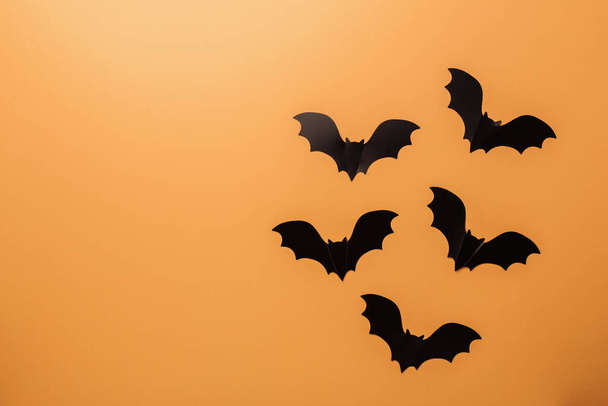 Halloween decorations concept. Black paper bats on orange background. Top view Copy space - Fotografie, Obrázek