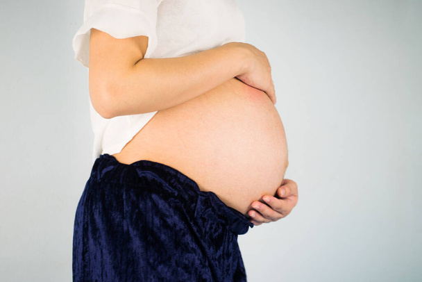 Junge schöne schwangere Frau berührt ihren Bauch. - Foto, Bild