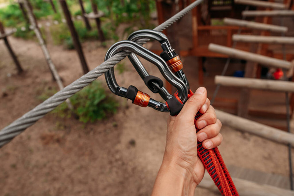 Rope park. The hand hooks the carabiners to the belay line. Close-up - Photo, Image