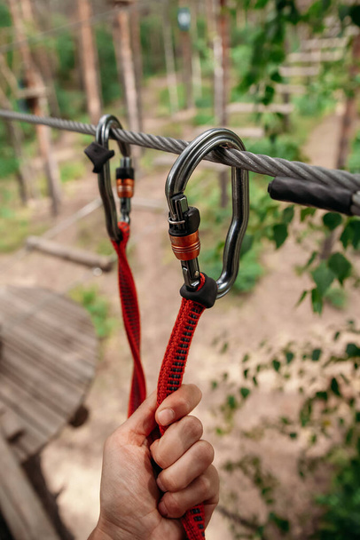 Rope park. The hand hooks the carabiners to the belay line. Close-up - Photo, Image