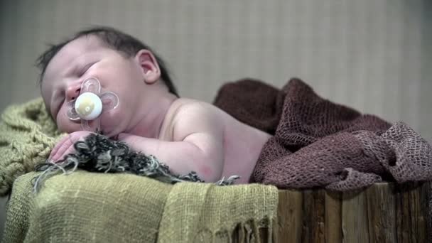 茶色のスカーフと毛布で覆われて、彼の口におしゃぶりを赤ちゃんが眠る - 映像、動画