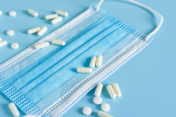 Pills and a medical mask on a blue background. Quarantine. - Фото, зображення