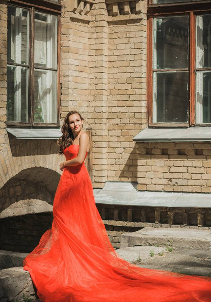 Βραδινά φορέματα έννοια, κομψό φανταχτερό στυλ. Γυναίκα με κόκκινο φόρεμα. Ρούχα για κυρίες, έμπνευση  - Φωτογραφία, εικόνα