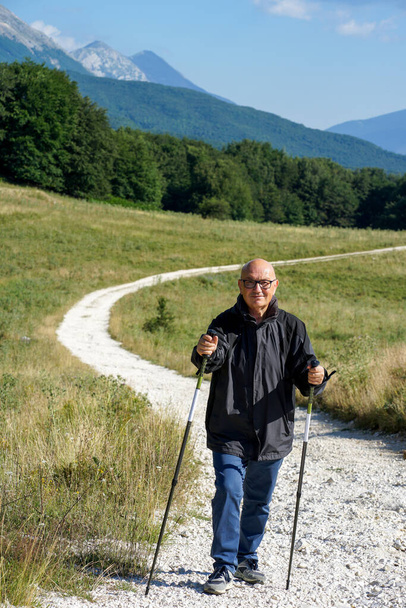 randonneur senior homme marchant dans une rue blanche - décor d'automne au Passo San Leonardo, Pacentro, Abruzzes, Italie, Parc national Maiella - Photo, image
