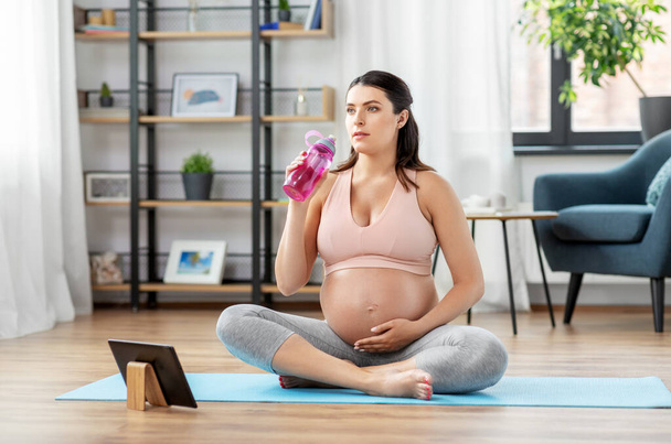 pregnant woman drinking water after yoga at home - Fotoğraf, Görsel