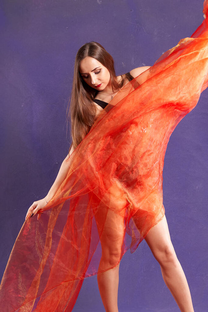 une belle fille blanche et en forme, dansant avec une ceinture orange.                                         - Photo, image