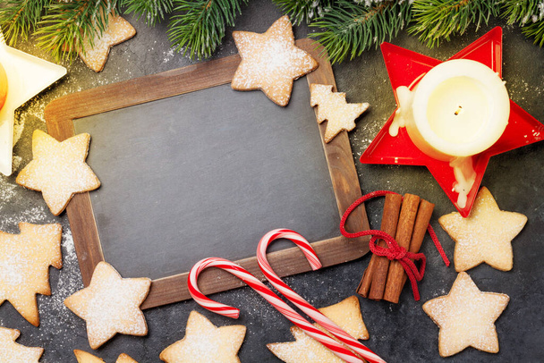 Carte de voeux de Noël avec sapin, biscuits au pain d'épice et bougies sur fond de pierre. Vue de dessus plat avec tableau noir pour vos salutations de Noël - Photo, image