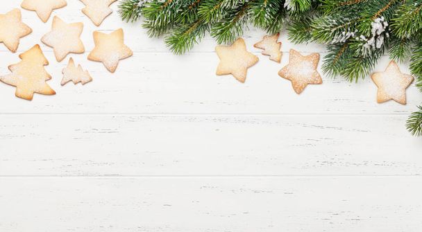 Рождественское пряничное печенье и ветка елки на деревянном фоне. Вид сверху с местом для приветствия - Фото, изображение