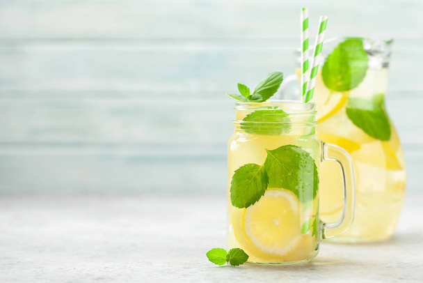 Mason pot en kruik met citroen en munt zelfgemaakte limonade. met kopieerruimte - Foto, afbeelding
