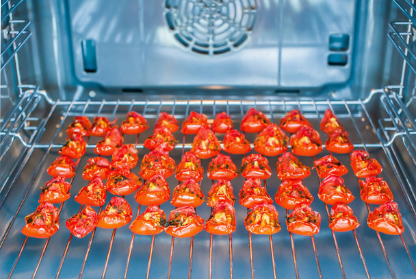 Kawałki suszonych na słońcu pomidorów na półce z drutu w piekarniku - Zdjęcie, obraz