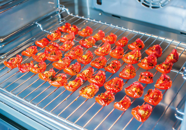 Tranches de tomates séchées au soleil sur un support métallique dans le four. Plan d'ensemble - Photo, image