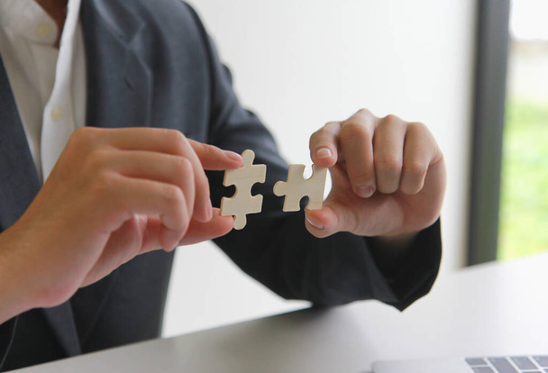 Un homme utilise les deux mains pour essayer de connecter les deux puzzles ensemble. symbole d'association et de connexion. concept de soutien et d'aide. - Photo, image