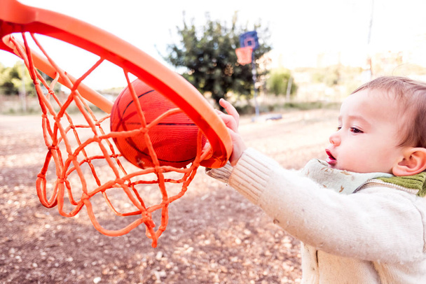 赤ちゃんはバスケットボールのおもちゃのバスケットでボールを打つしようとします. - 写真・画像